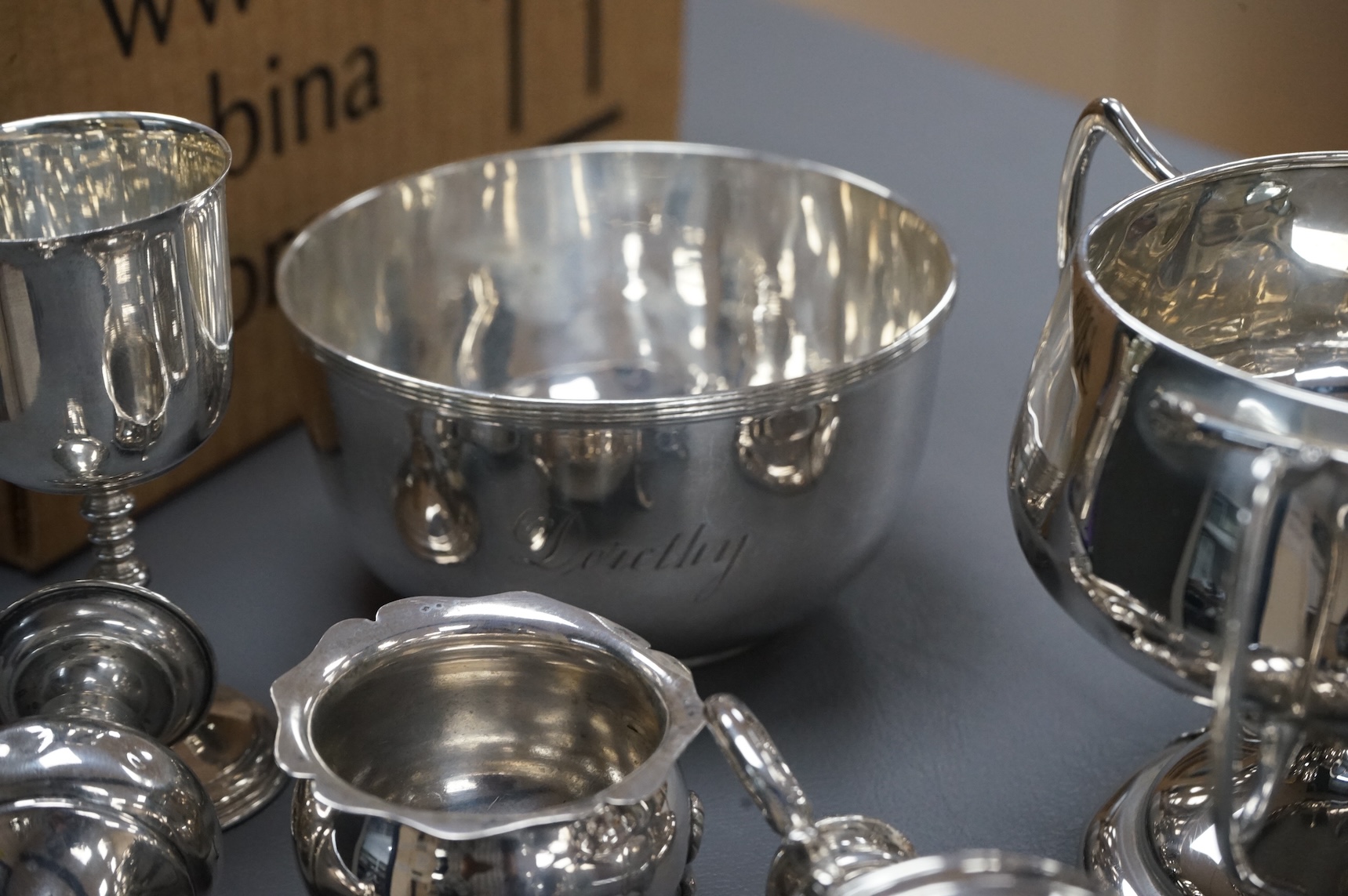 A collection of small silver including an Edwardian Art Nouveau tri-handled pedestal bowl, Birmingham, 1909, height 90mm, a sugar bowl, three cigarette cases, goblet, communion jug, five condiments, three napkin rings, e